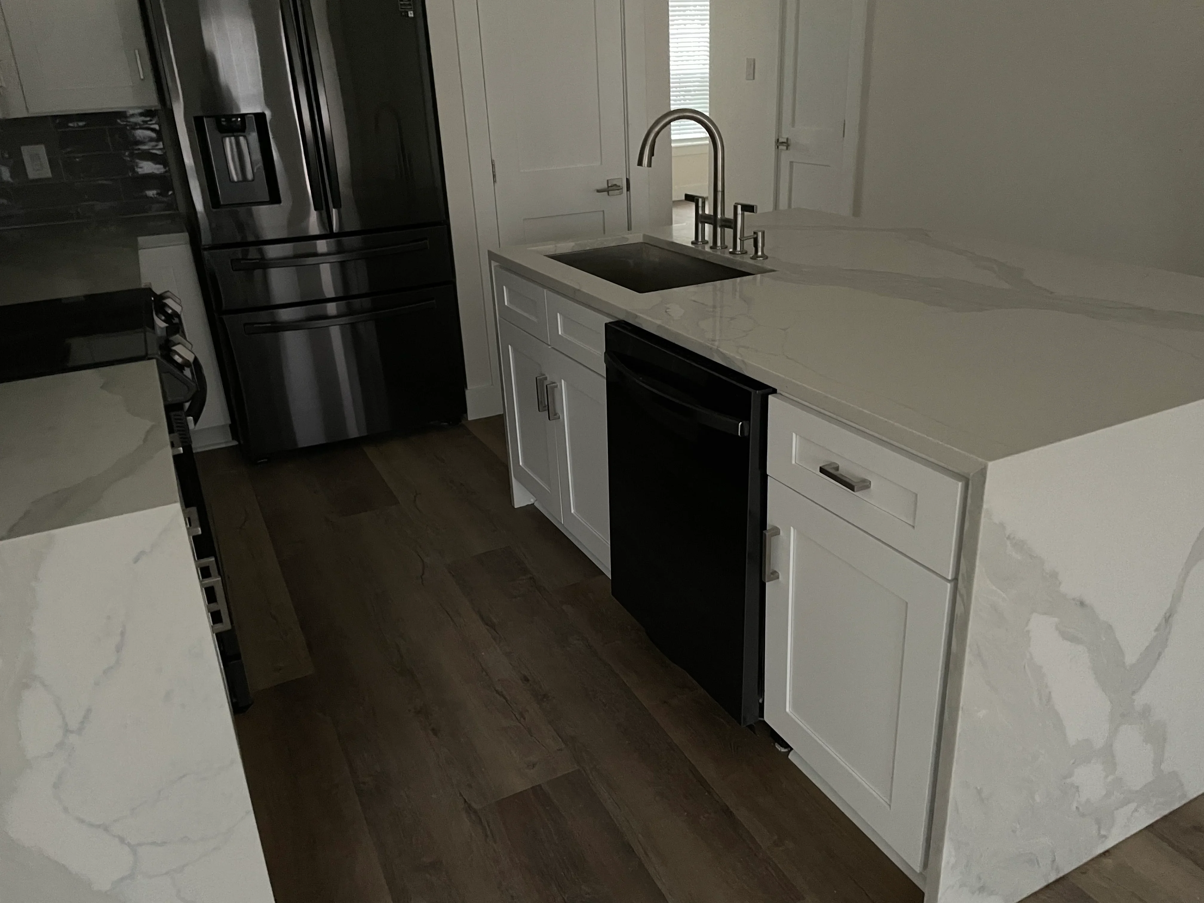 Restored kitchen with white cabinets, quartz counters, stainless steel appliances, and dark wood flooring