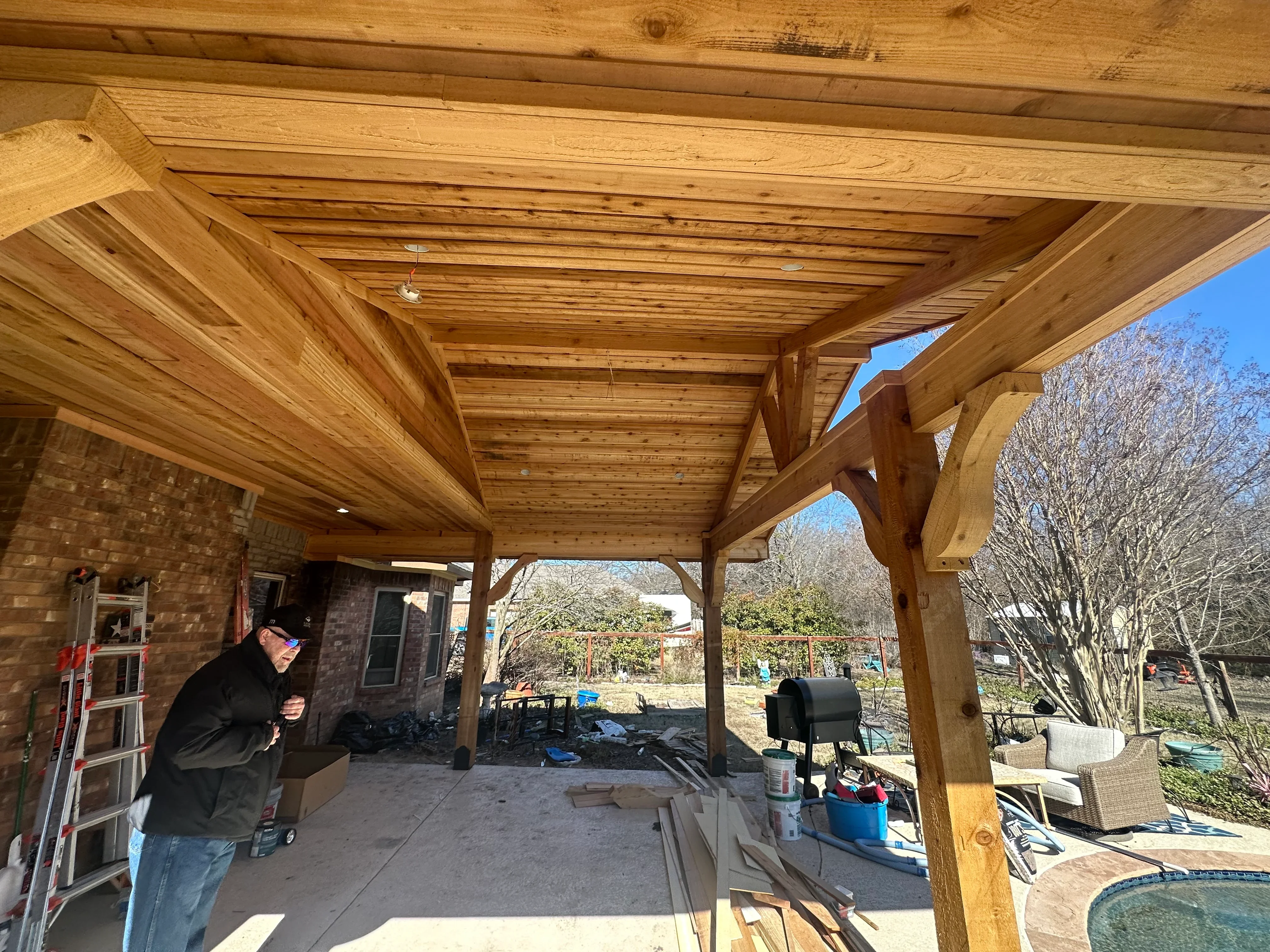 Wooden beam patio cover with slatted ceiling, timber posts, and concrete foundation