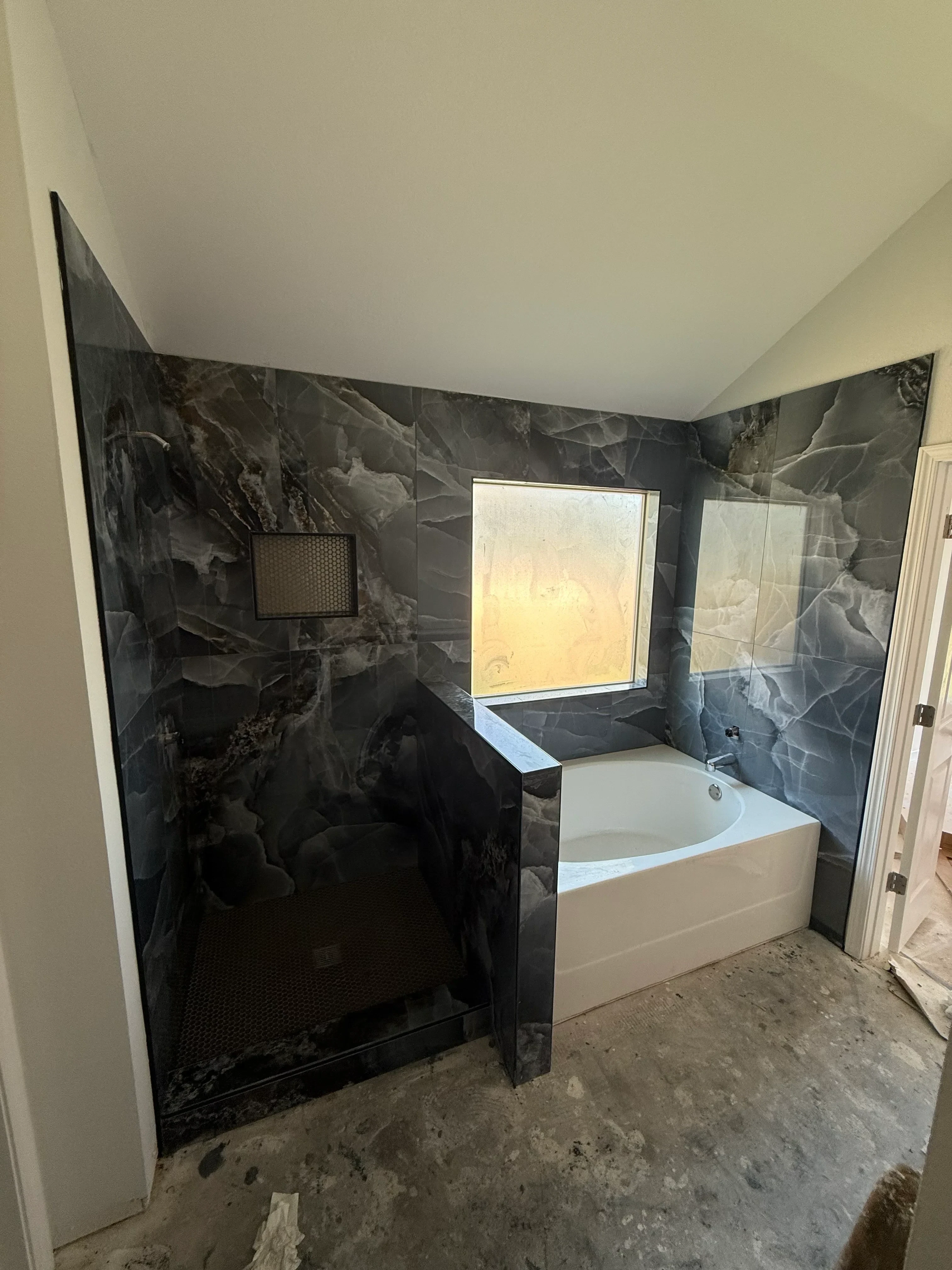 Dark marble tile bathroom with white vanity, floor drain, and skylight window