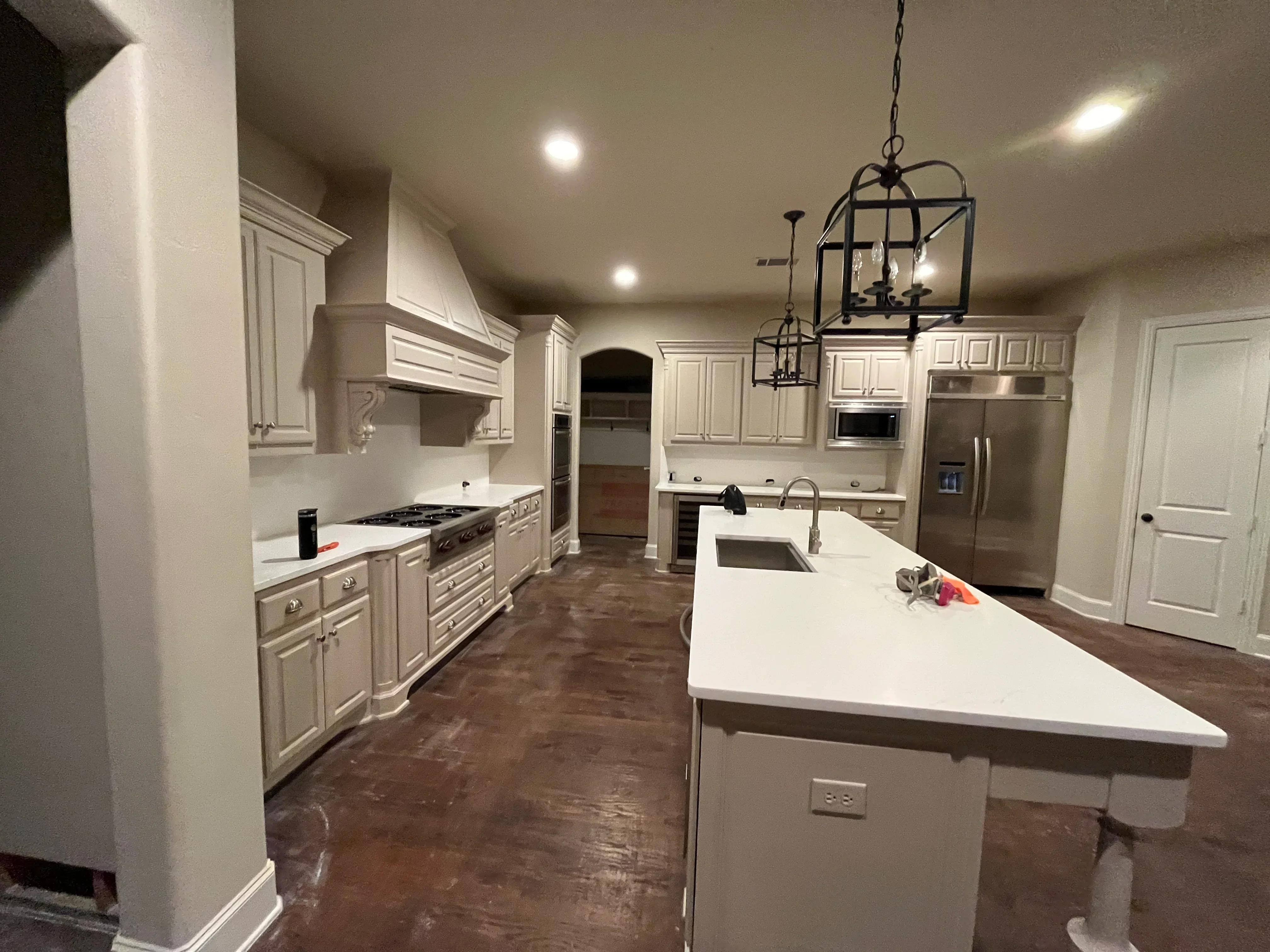 Restored kitchen with cream cabinets, white quartz counters, hardwood flooring, and stainless steel appliances