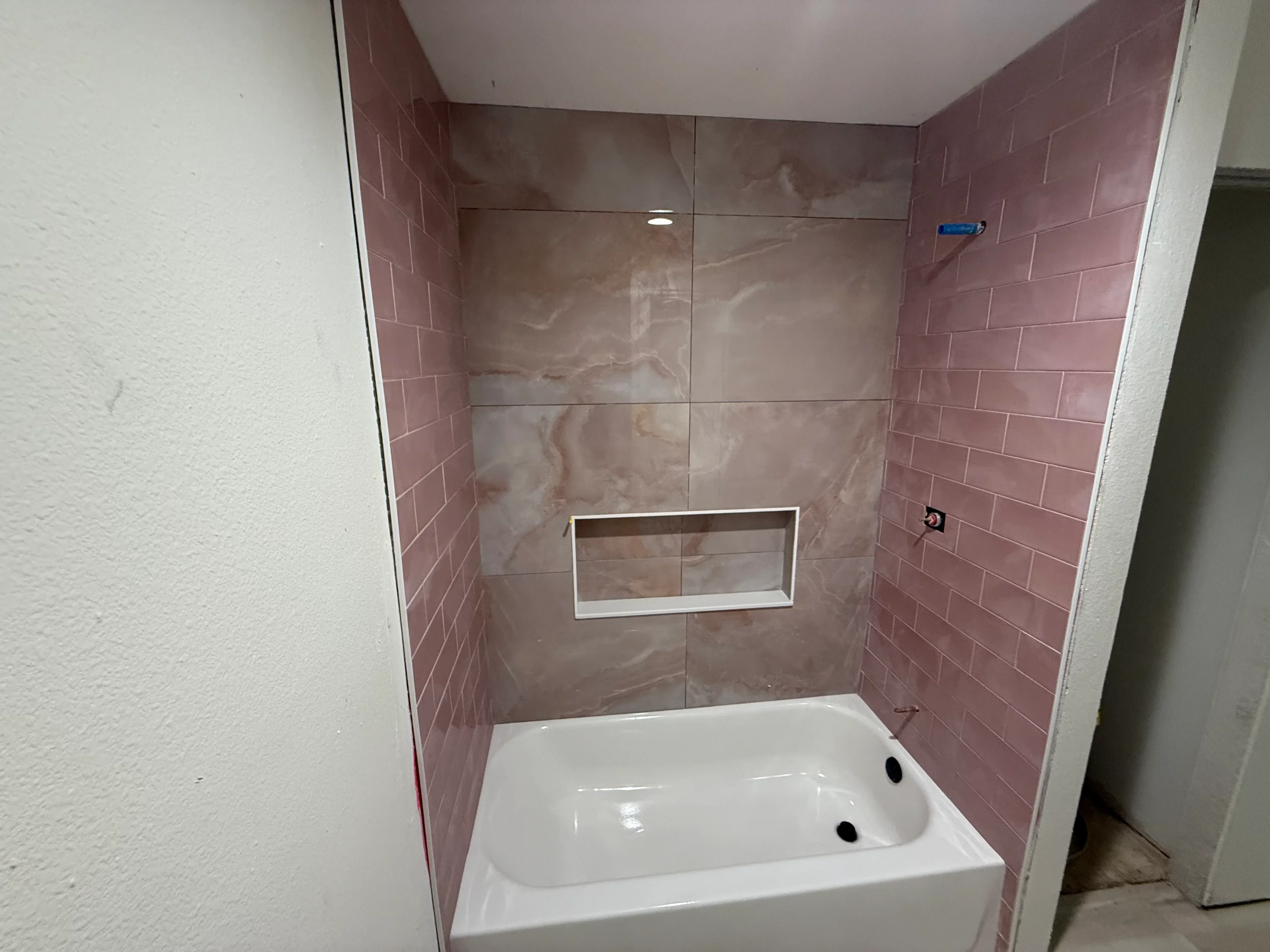 Mauve subway tile shower with frameless glass enclosure and white bathtub