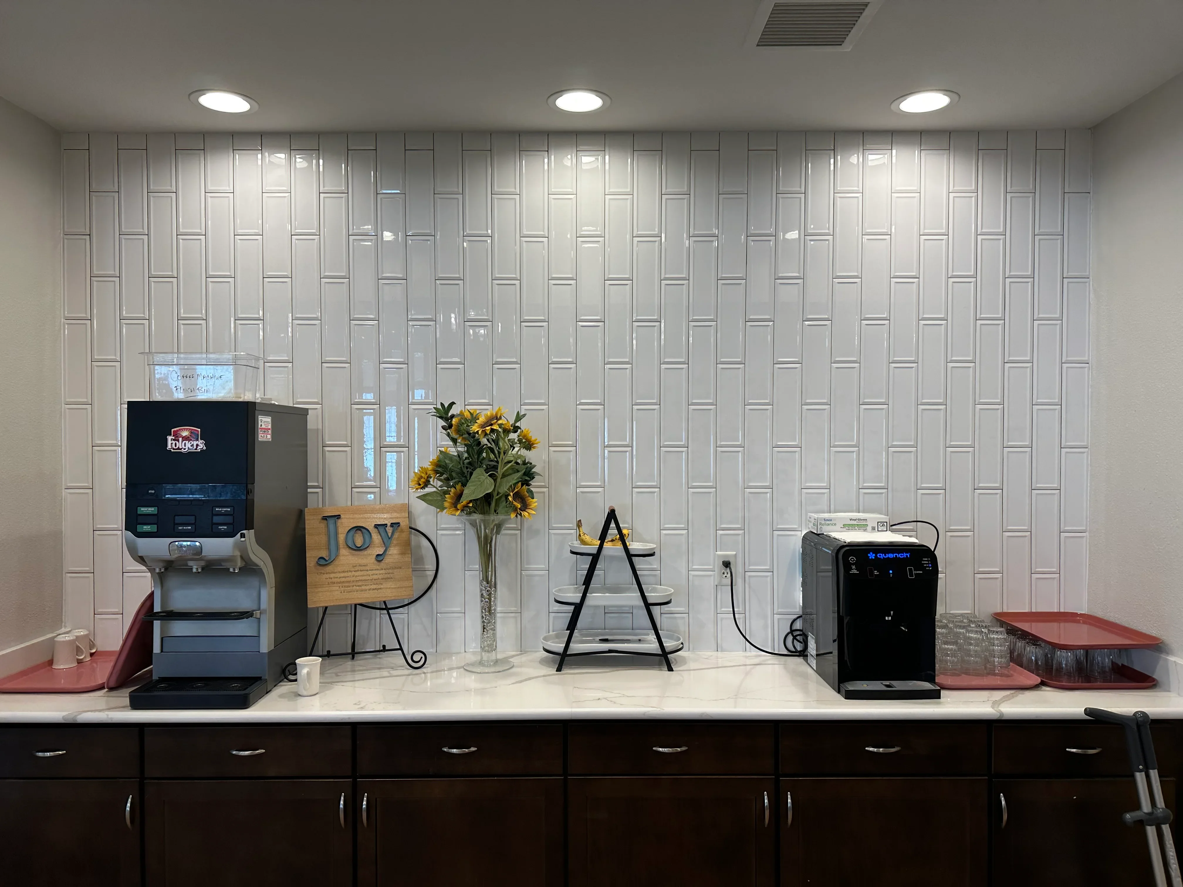 Restored break room with white subway tile wall, recessed lighting, dark cabinetry, and white quartz countertop