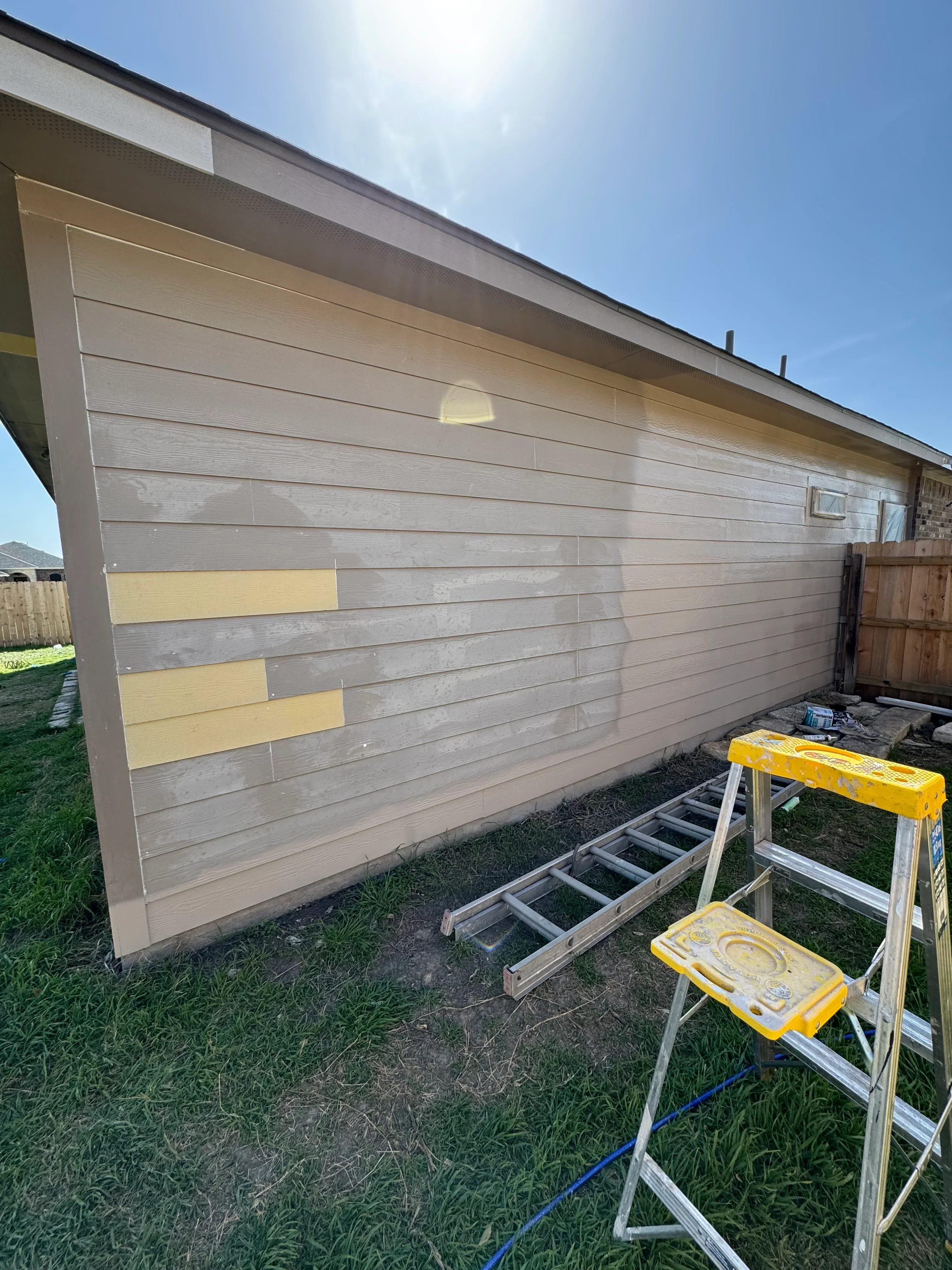 Composite deck with gray and yellow boards during restoration, with ladders and work equipment visible