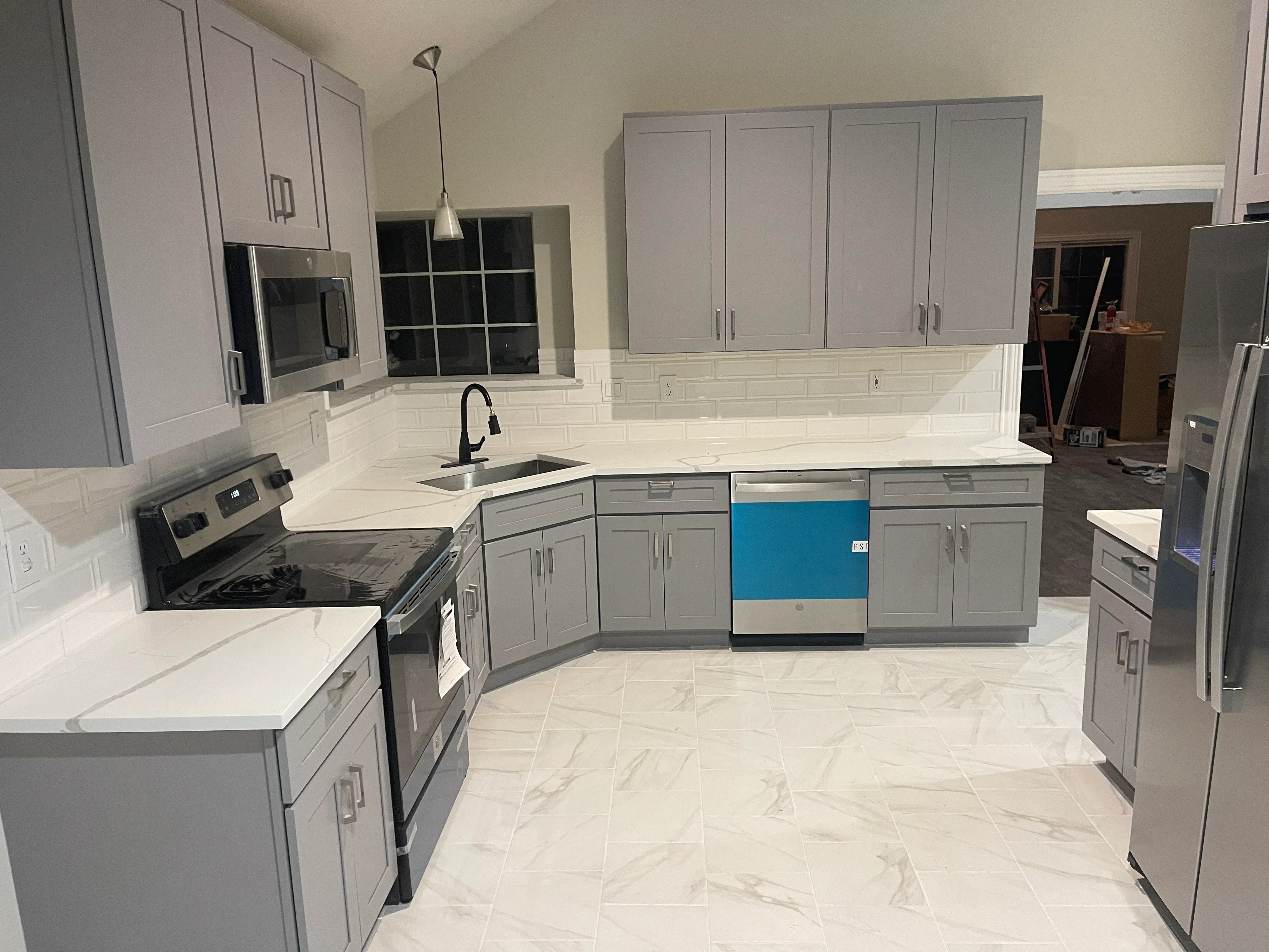 Gray kitchen cabinets with white quartz counters, subway tile backsplash, and marble-look tile flooring